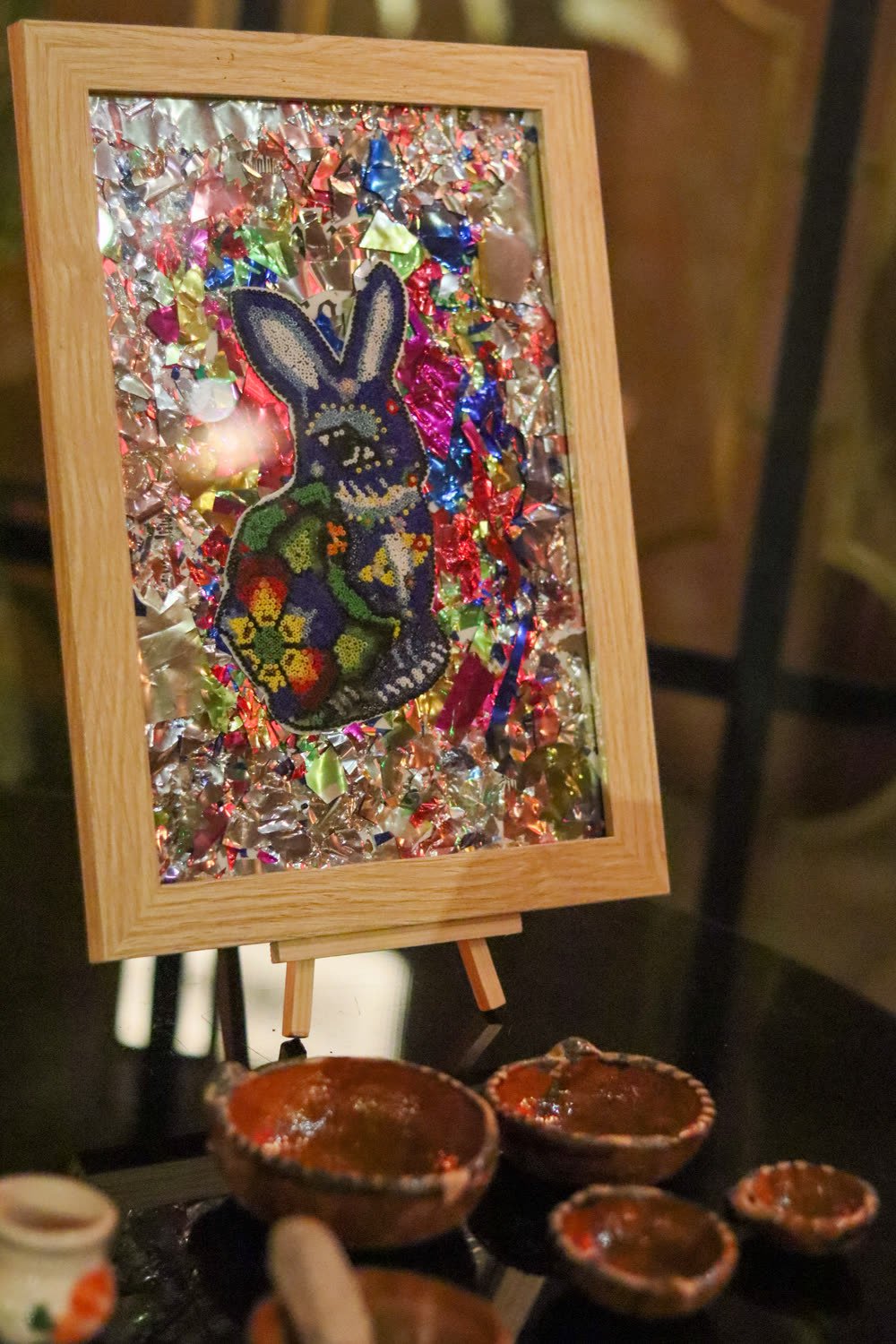 Huichol-style beaded rabbit artwork displayed on an easel