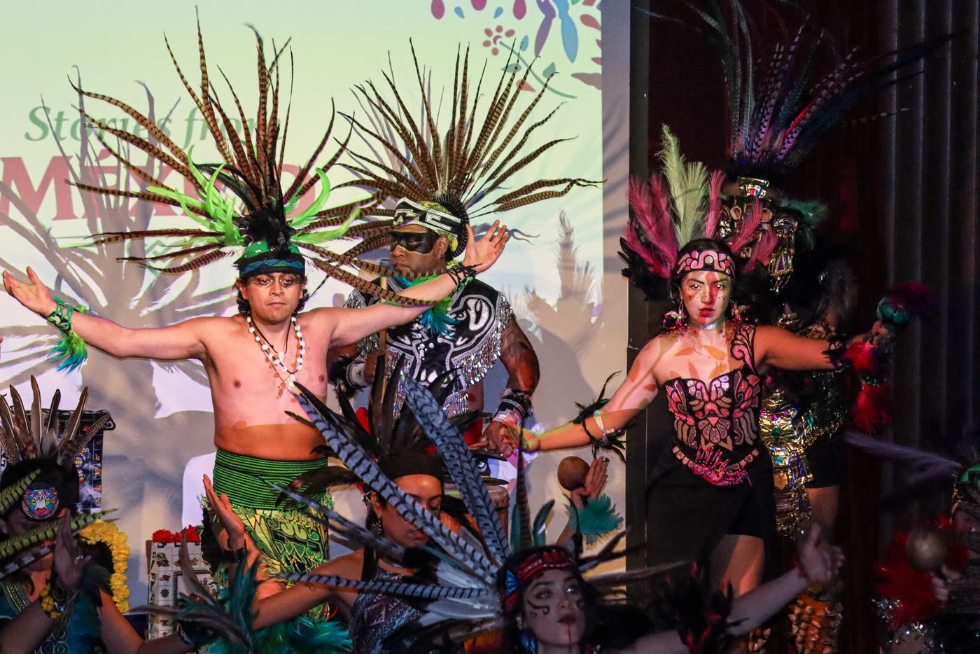 Calpulli Mictlán dancers in full Aztec regalia on stage