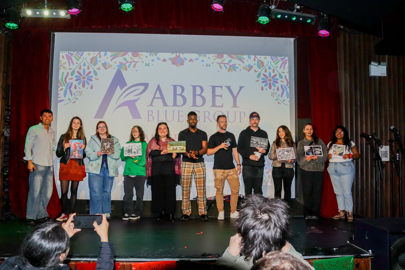 Exhibiting artists on stage with the Abbey Blue Group backdrop
